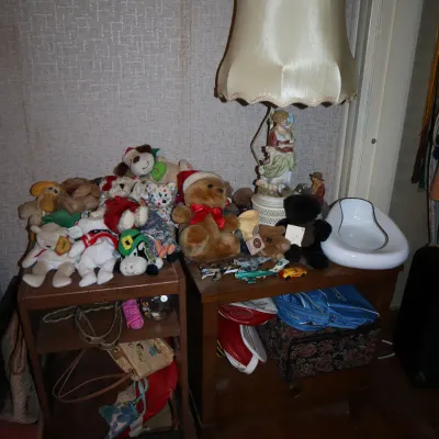 Sale Photo Thumbnail #157: Collection of Beanie Babies and plush toys displayed on wooden nightstands alongside a vintage figurine table lamp.