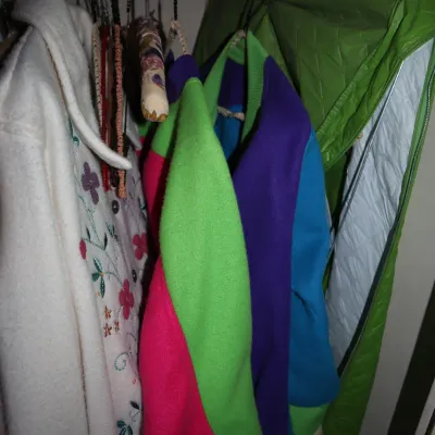 Sale Photo Thumbnail #152: Selection of vintage outerwear hanging in a closet, including a 1980s color-block jacket and an embroidered white fleece coat.