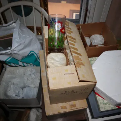 Sale Photo Thumbnail #52: Vintage floral printed drinking glass packed in its original cardboard box among various other packed household items.