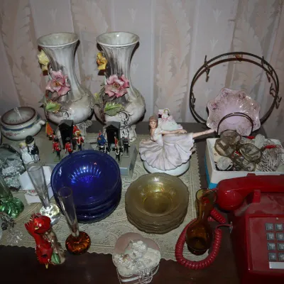 Sale Photo Thumbnail #109: Collection of vintage table top collectibles including a red push-button telephone, porcelain floral vases, ballerina figurine, glass bud vases, and cobalt blue bowls.