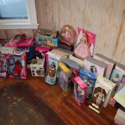 Sale Photo Thumbnail #84: Collection of vintage and modern Barbie dolls in original packaging, including Holiday Barbie and Special Edition releases, arranged on a wooden floor.