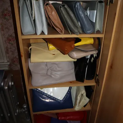 Sale Photo Thumbnail #21: Collection of vintage women's clutch purses and handbags organized on wooden cabinet shelves.
