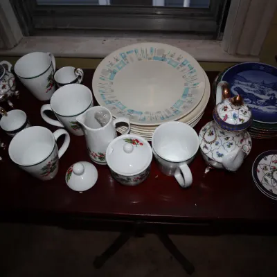 Sale Photo Thumbnail #134: Assorted vintage ceramics and tableware including a holly-patterned tea set, mid-century atomic pattern dinner plates, and decorative collector plates.