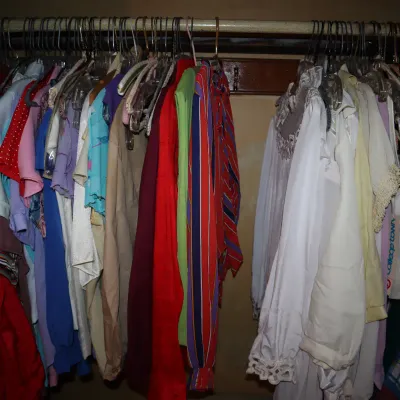 Sale Photo Thumbnail #32: Closet filled with assorted vintage clothing, featuring colorful tops, dresses, and blouses on hangers.