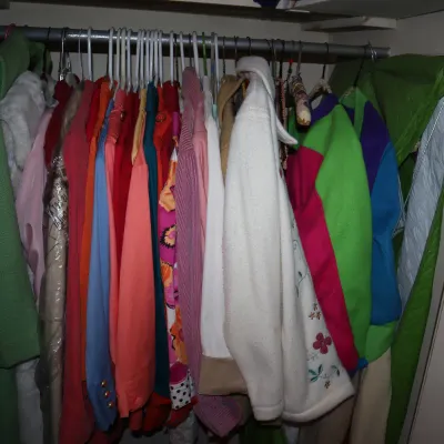 Sale Photo Thumbnail #151: Closet rod filled with colorful vintage women's clothing, including jackets, blouses, and dresses in various fabrics and patterns.