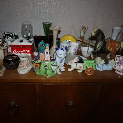 Sale Photo Thumbnail #148: Large collection of vintage ceramic and glass knick-knacks, including a Coca-Cola cooler box, animal figurines, vases, and small decorative trinkets displayed on a wooden cabinet.