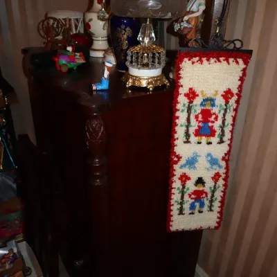 Sale Photo Thumbnail #54: Dark wood vintage dresser topped with decorative lamps, ceramics, and a hanging Scandinavian-style needlepoint tapestry.