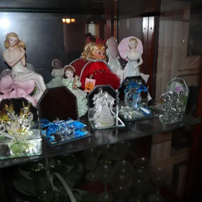 Sale Photo Thumbnail #117: Collection of decorative porcelain, resin, and crystal glass figurines displayed inside a glass curio cabinet.