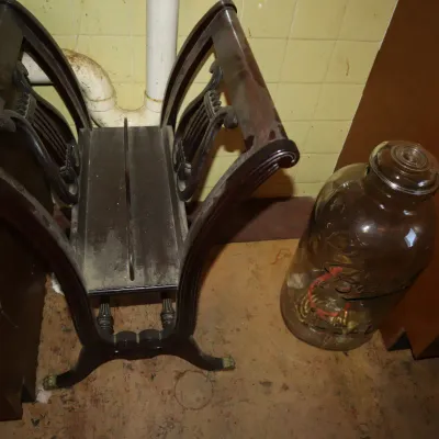Sale Photo Thumbnail #138: Vintage dark wood lyre-back magazine rack or vanity stool frame alongside a large glass jar.