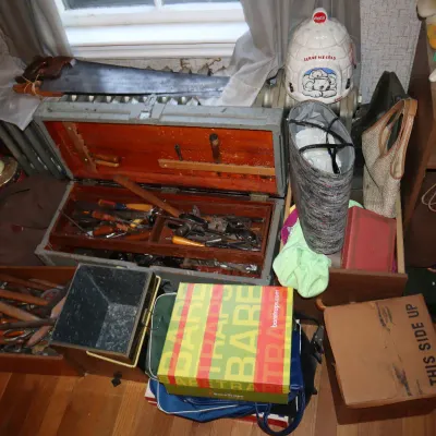 Sale Photo Thumbnail #159: A wooden tool chest filled with vintage hand tools, accompanied by hand saws, plush toys, handbags, and various household storage boxes.