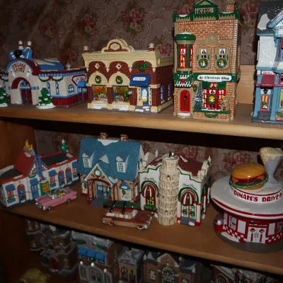 Sale Photo Thumbnail #13: Collection of Department 56 and Lemax miniature Christmas village buildings and accessories displayed on wooden shelves.