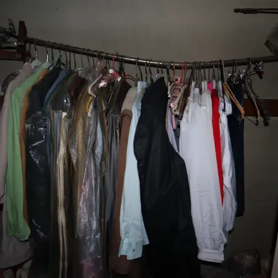 Sale Photo Thumbnail #81: Collection of vintage women's clothing, coats, and garment bags hanging on a closet rod.