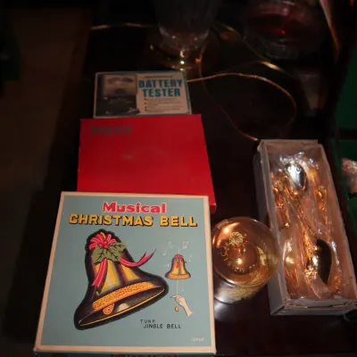 Sale Photo Thumbnail #123: Vintage items including a boxed Japanese Musical Christmas Bell, a battery tester, a small red box, and a set of decorative gold-tone spoons.