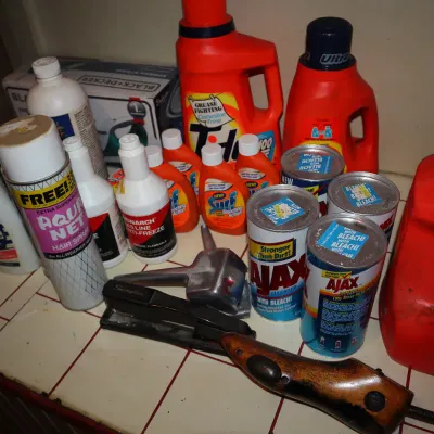 Sale Photo Thumbnail #145: Assortment of vintage household supplies including Aqua Net hair spray, Tide laundry detergent, Ajax cleanser cans, and a stapler.
