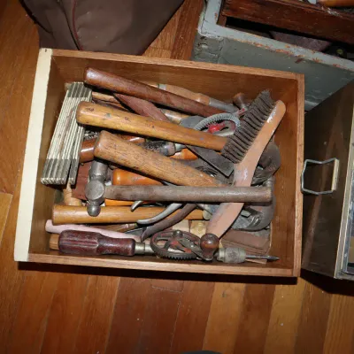 Sale Photo Thumbnail #161: Wooden box filled with assorted vintage hand tools, including hammers, a hand drill, a folding ruler, and a wire brush.