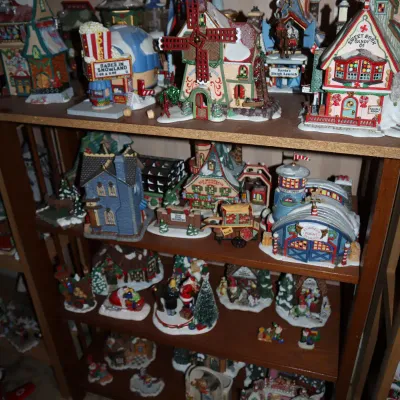 Sale Photo Thumbnail #38: Collection of Dept 56 and North Pole Series Christmas village buildings and figurines displayed on wooden shelving units.