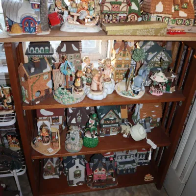 Sale Photo Thumbnail #20: Wooden four-tier bookcase filled with an extensive collection of vintage porcelain Christmas village buildings, figurines, and holiday decorations.