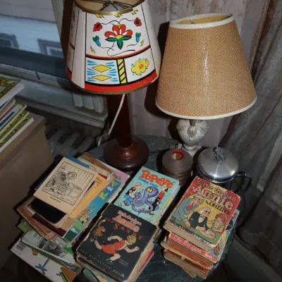 Sale Photo Thumbnail #99: Collection of vintage Big Little Books including Popeye and Little Orphan Annie, displayed on a table with two small table lamps.