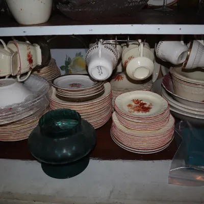 Sale Photo Thumbnail #112: Collection of vintage floral-patterned china dishware, including stacked plates, bowls, hanging teacups, and a green glassware vase.