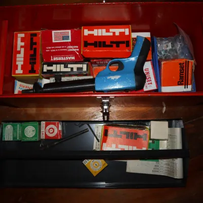 Sale Photo Thumbnail #91: Vintage powder-actuated fastening tool kit with Hilti and Ramset supplies, housed in a red metal toolbox.