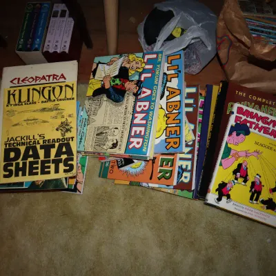 Sale Photo Thumbnail #100: Collection of vintage comic strip compilation books and reference manuals, including Li'l Abner, Bringing Up Father, and Star Trek technical data sheets.