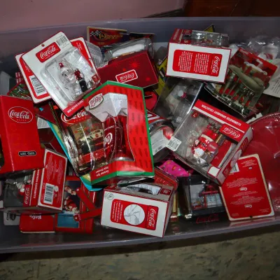 Sale Photo Thumbnail #165: Large plastic storage tub filled with vintage packaged Coca-Cola Christmas ornaments, collectibles, and novelty items.