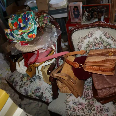 Sale Photo Thumbnail #43: Collection of vintage handbags, purses, and straw totes piled atop two floral tapestry upholstered armchairs.