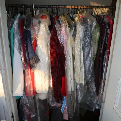 Sale Photo Thumbnail #22: Closet full of vintage women's clothing, featuring coats and dresses protected in clear plastic garment bags.