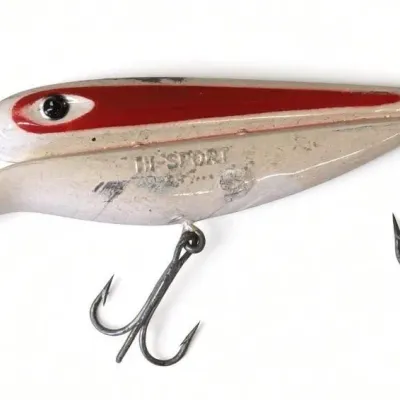 Sale Photo Thumbnail #114: Lot 187: Vintage hard-plastic fishing lure, white body with bold red stripe and black eye. Long diving lip/bill, two treble hooks, and “HI-SPORT” marking visible on the side