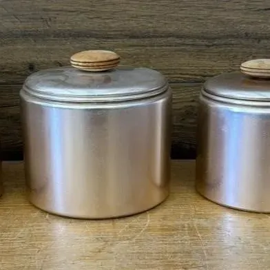 Sale Photo Thumbnail #396: Lot 497: 1950s Mirro graduated canister set - rose-gold anodized aluminum with round wooden knobs