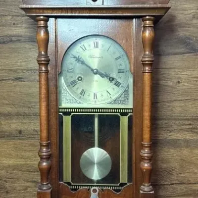 Sale Photo Thumbnail #579: Lot 683: Wentworth wall clock unknown condition vintage 31-day mechanical wall clock featuring a wooden case, Roman numeral dial, glass front door, gold-tone pendulum, and a winding key hole at the bottom