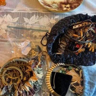Sale Photo Thumbnail #66: Collection of vintage costume jewelry, including beaded necklaces and metallic chains, contained in drawstring fabric pouches, alongside a hand-painted porcelain dish.