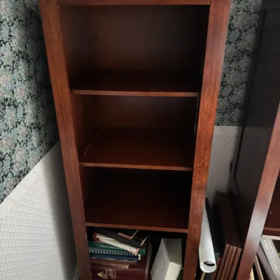 Sale Photo Thumbnail #135: Tall, modern reddish-brown wood bookcase featuring four open shelf compartments, shown with assorted books on the bottom shelf.