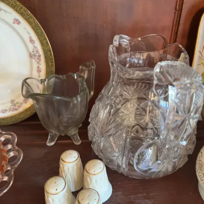 Sale Photo Thumbnail #402: Collection of vintage glassware and tableware, including a heavy American Brilliant cut glass pitcher, a footed glass creamer, and porcelain salt and pepper shakers with gold trim.