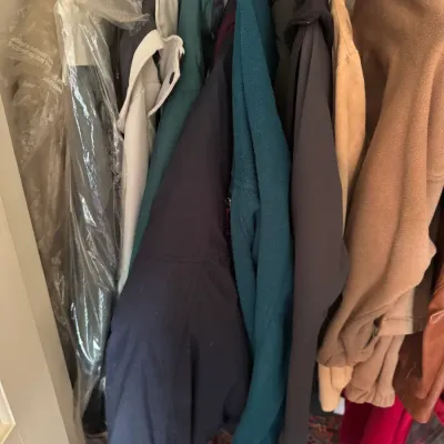 Sale Photo Thumbnail #279: Collection of assorted winter coats and jackets hanging in a closet, including fleece, wool, and fur-trimmed outerwear.