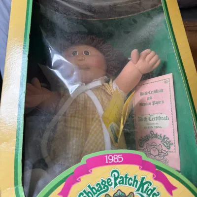 Sale Photo Thumbnail #118: Vintage 1985 Cabbage Patch Kids doll, named Aileen Edna, preserved in its original box with included birth certificate and adoption papers.