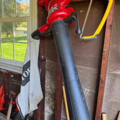 Sale Photo Thumbnail #205: Red Toro electric leaf blower and vacuum with attached collection bag, hanging alongside a yellow and black Stanley hacksaw.