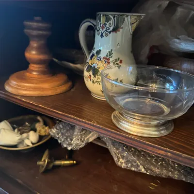 Sale Photo Thumbnail #382: Collection of tabletop decor displayed on a shelf, including a hand-painted floral ceramic pitcher, a clear glass bowl with a metal base, and a turned wood candlestick holder.