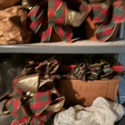 Sale Photo Thumbnail #87: Collection of holiday decorations including festive red and green plaid bows with gold wire trim and boxed candles stored on shelves.