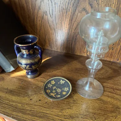 Sale Photo Thumbnail #296: Collection of decorative miniature items including a cobalt blue Greek revival vase with gilt detailing, a small patterned saucer, and a clear glass oil lamp.