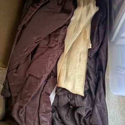 Sale Photo Thumbnail #370: Cardboard box filled with assorted vintage fabrics, drapes, and textiles in shades of brown and beige.