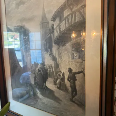 Sale Photo Thumbnail #384: Framed black-and-white art print depicting a vintage European village street scene, set under glass in a dark wooden frame with an off-white mat board.