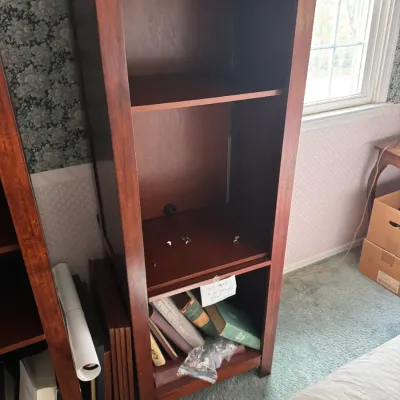 Sale Photo Thumbnail #136: Tall cherry-finished wood media cabinet or bookcase with adjustable shelving, wire management cutout, and lower storage compartment containing books.