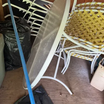 Sale Photo Thumbnail #35: Vintage outdoor patio furniture set stored in a shed, including a round glass-top table, yellow-strapped lawn chairs, and lounge chairs.