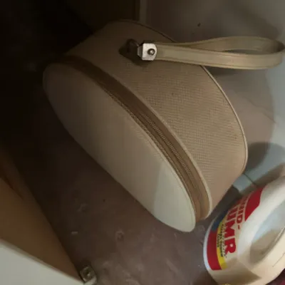 Sale Photo Thumbnail #141: Vintage beige round hat box luggage with a carrying handle and zippered closure, sitting on the floor of a closet.