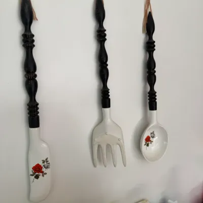 Sale Photo Thumbnail #213: Set of three vintage giant wall-hanging utensils featuring dark turned-wood handles and white ceramic bases with red rose decals.
