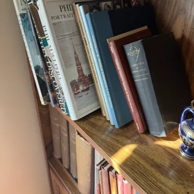 Sale Photo Thumbnail #297: Collection of hardbound history, geography, and reference books arranged on a wooden bookcase, including titles like 'Philadelphia Discovered' and Bruce Catton's 'A Stillness at Appomattox'.