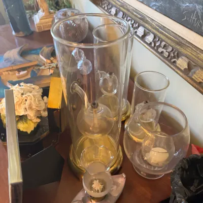 Sale Photo Thumbnail #349: Collection of decorative clear glass items, including a tall cylinder vase with internal spherical oil lamps, small glass votives, and tabletop accessories.