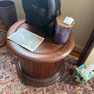 Sale Photo Thumbnail #290: Round wooden tambour side table holding a black Honeywell desk fan, a jar candle, and a vintage photograph.