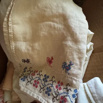 Sale Photo Thumbnail #371: Vintage off-white linen cloth featuring colorful cross-stitch embroidery along the border, including small roosters and floral vines.